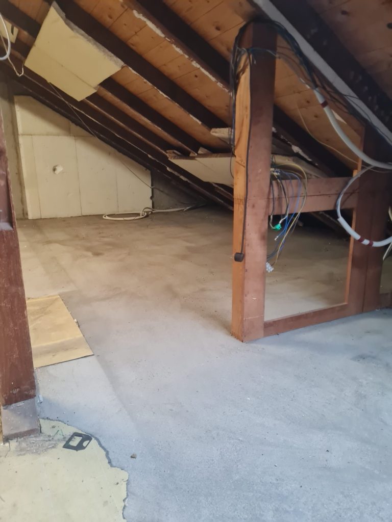 Dachboden mit Holzstützen und freiem Boden, unbenutzt und hell erleuchtet.